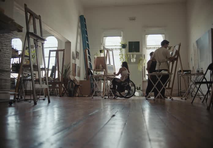 A group of artists painting with oil over canvas in a studio
