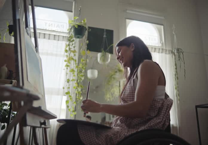 A woman in wheelchair painting indoor
