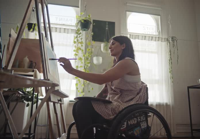 A woman on a wheelchair does a painting