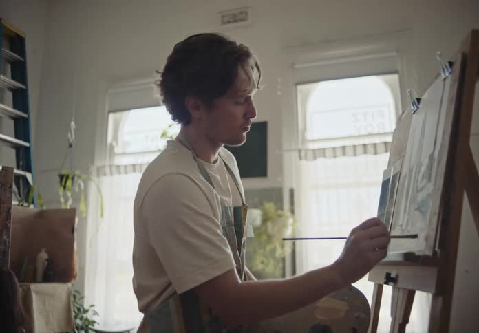 A clip of a male artist painting on a board