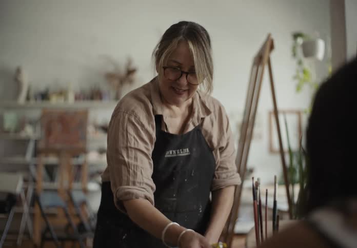An artist talking to a friend while mixing oils in the studio