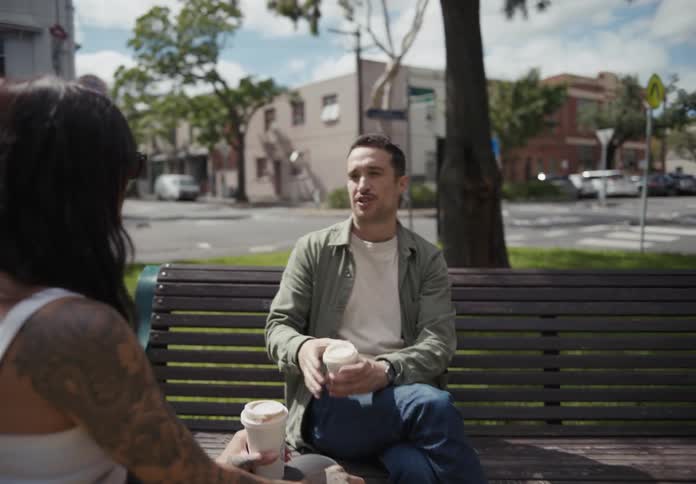 Friends talking and sitting on a bench in the neighborhood square during the day