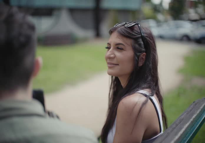 A woman and a man sitting on a park bench talking and laughing