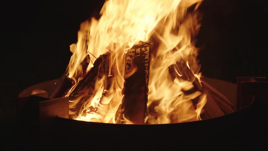 Closeup of glowing embers and flames in a fire at night
