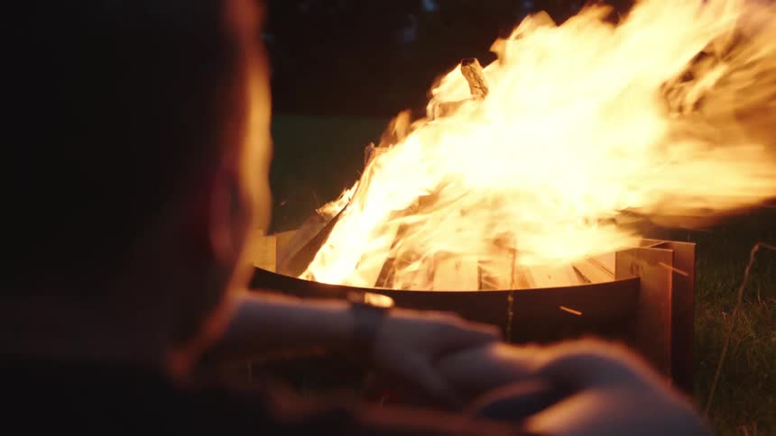 A clip of a person seating beside a burning fire