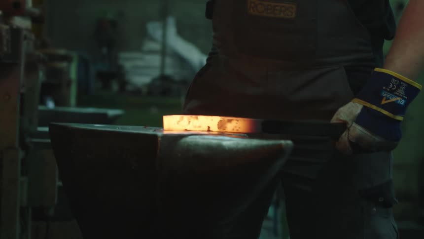A blacksmith handling a hot iron with a hammer