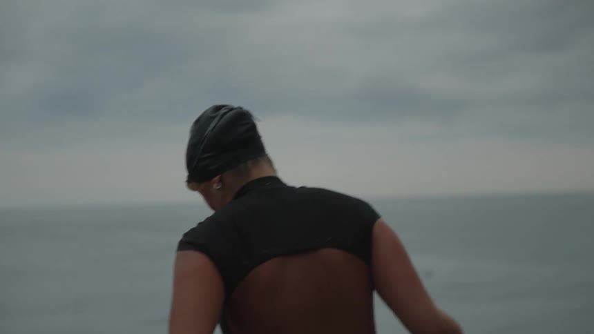 On a cloudy day a black woman in swimsuit walk towards the sea