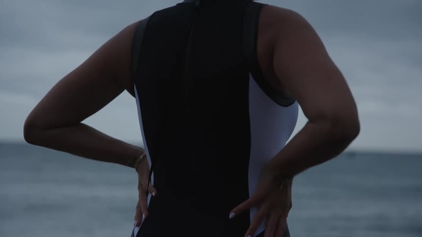 A woman in swimsuit standing and staring at the ocean