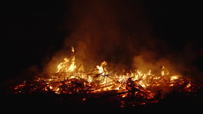 A large bonfire lit at night outdoors