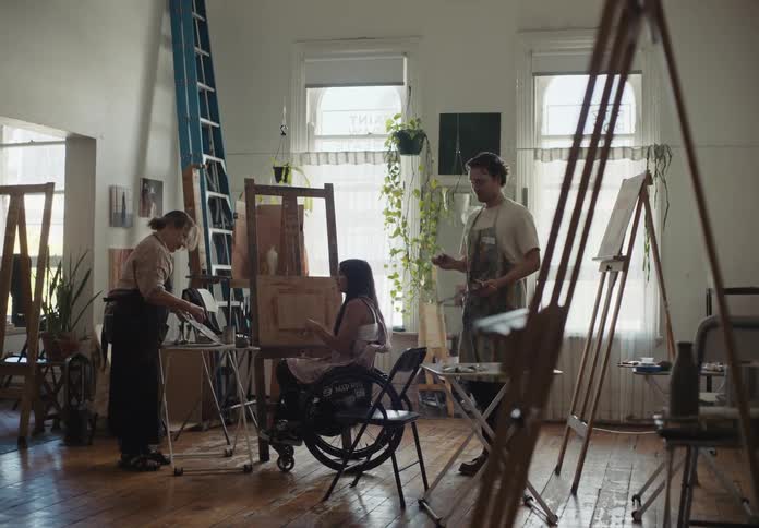 Three people in a room working with paint including a person in a wheelchair