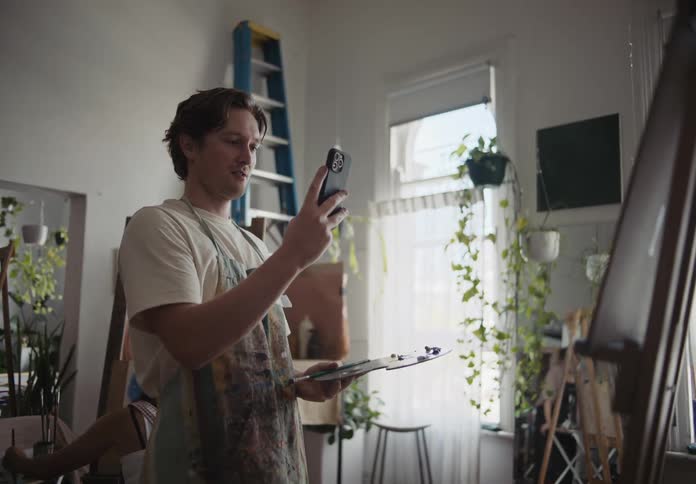 An artist uses his smartphone to take a photo of his painting