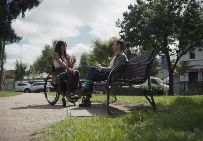 A man and woman smile and talk on a bench
