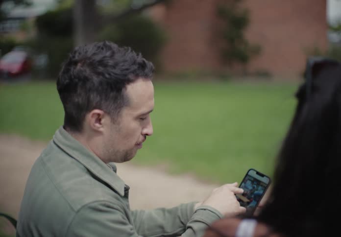 A man and a woman talking on a park bench