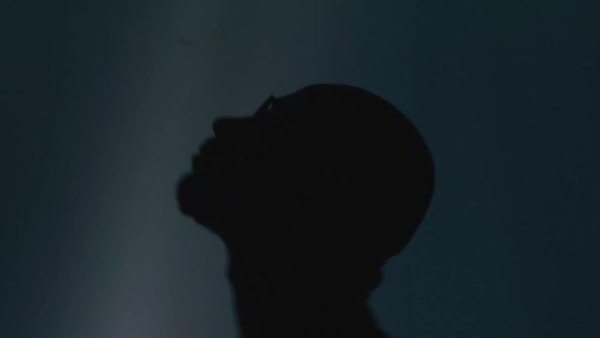 Silhouette of a man looking up in front of a projector