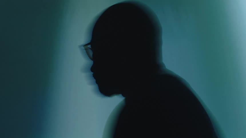 A bald man wearing glasses makes sudden sharp moves