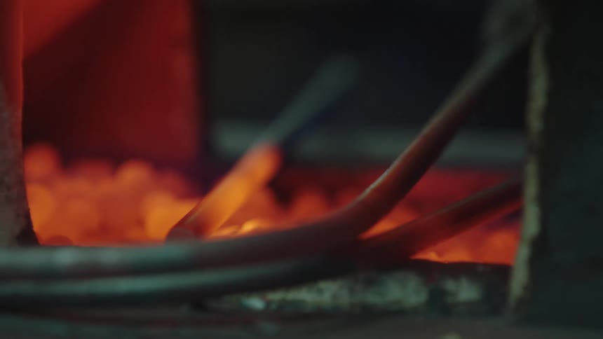 Closeup of a metal rod being placed on top of glowing stones