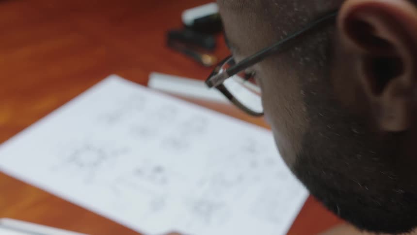 Closeup of a mans face writing on a table