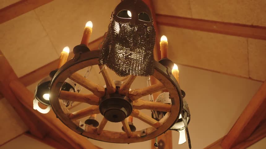A metal mask hangs on a wheel chandelier