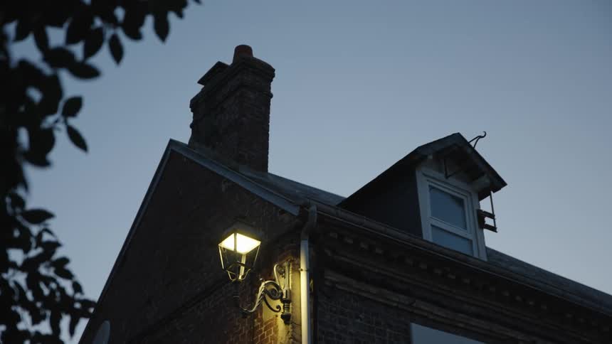 Upward view of a brick house with light fixtures at dawn