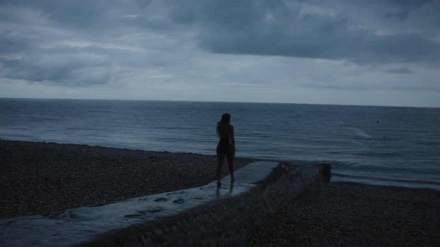 A woman walking towards the sea during dusk