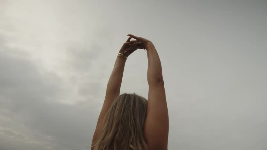 Back of a lady stretching both hands while standing outdoor during the day