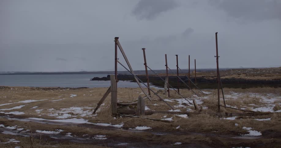 Wood posts line along a snowy shoreline