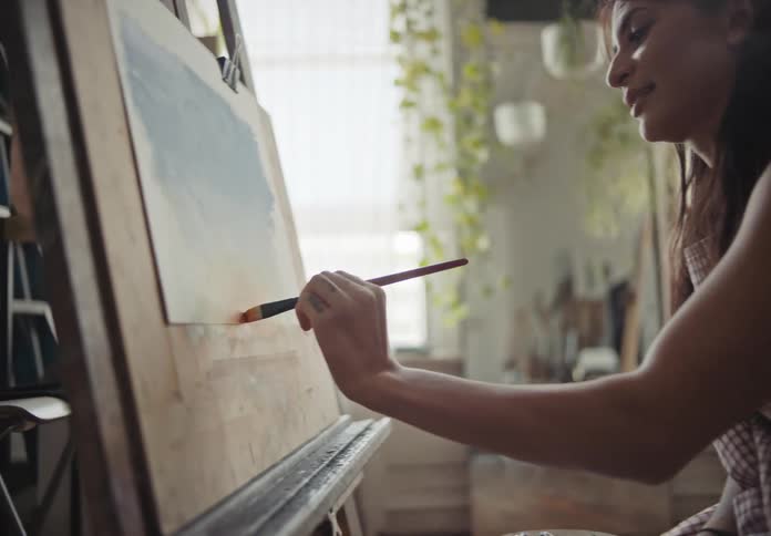 Wheelchair user woman painting on a canvas in front of her