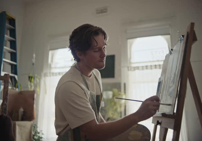 A man is painting on the easel