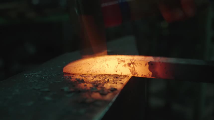 A blacksmith is hammering hot steel