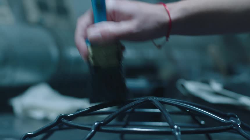 A person uses a brush to paint a metallic structure