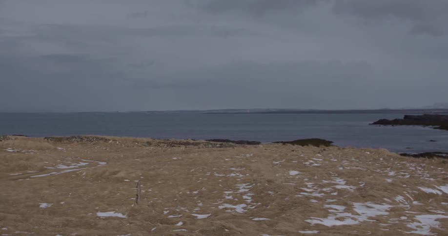 The field below by the water has some snow on it