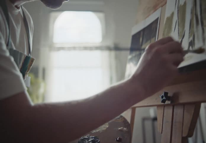 A man focused on painting a modern art canvas