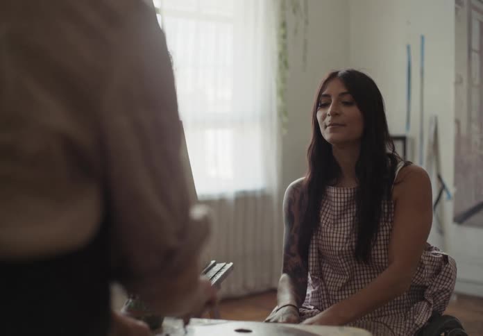 A woman in a wheelchair is talking to a woman who is standing and fiddling with something on a table in front of the two