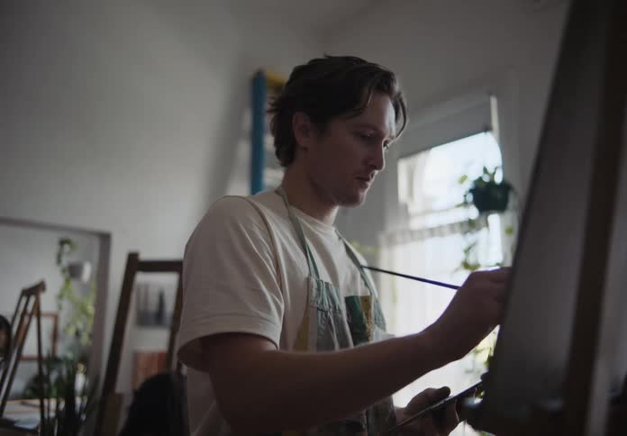 A man painting a modern art canvas in a room