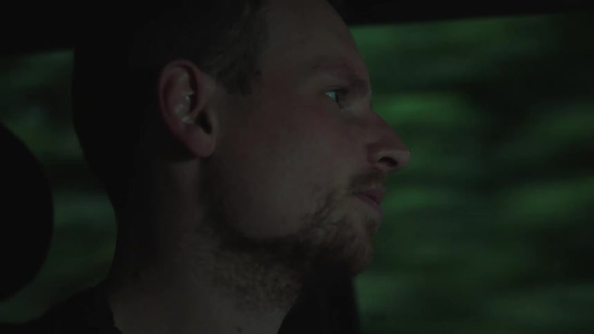 The face of a man who is inside a car and in the window you can see many trees passing quickly