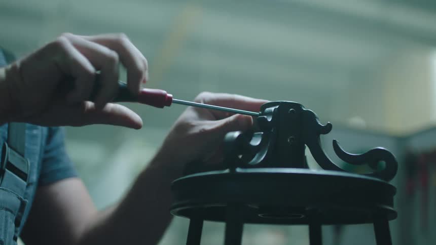 Hand of a man screwing a metal base with a wrench