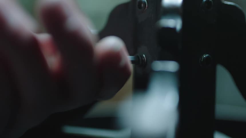 Closeup of fingers tightening a screw with a tool