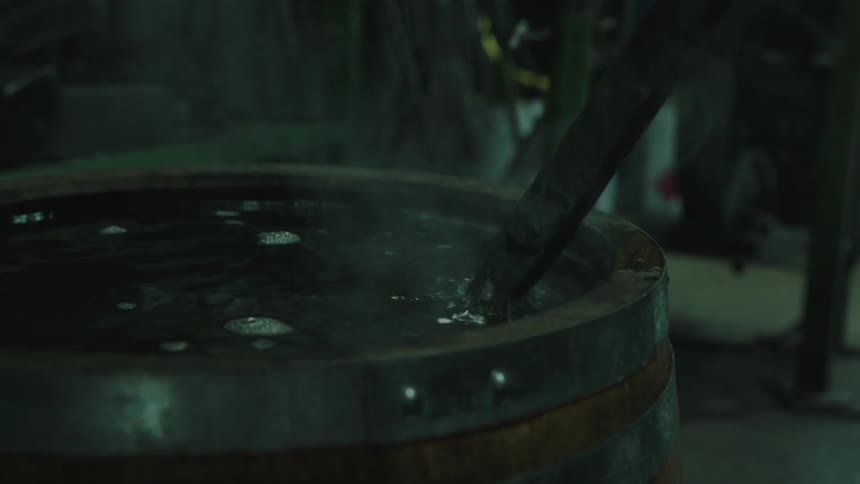 Closeup of iron being placed into a barrel of water emitting steam