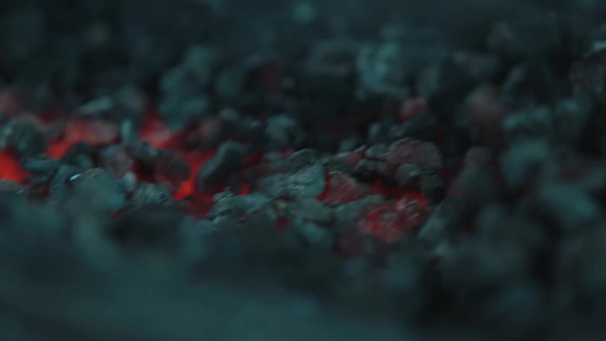 Closeup of a rod pushing a glowing charcoal