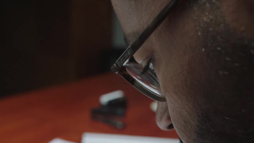 Close up of the face of a man with glasses working at the office