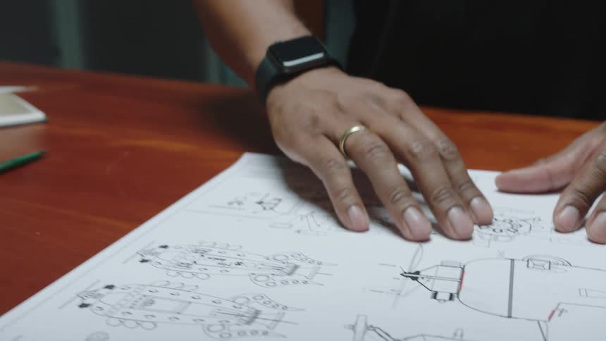 Hand of a man touching a blueprint over a desk