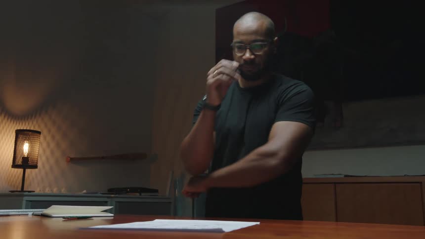 Man inside a room placing his hand on his mouth while analyzing a document on the table