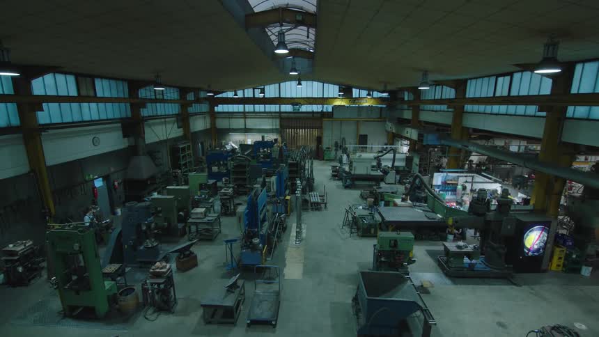 Some people working at a mostly empty factory in a warehouse