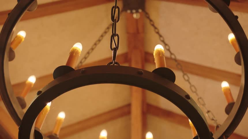 Upward view of a chandelier with lit artificial candles