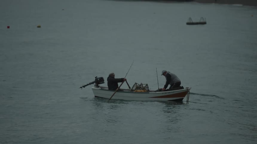 Two fishermen are rowing a boat on a peaceful lake