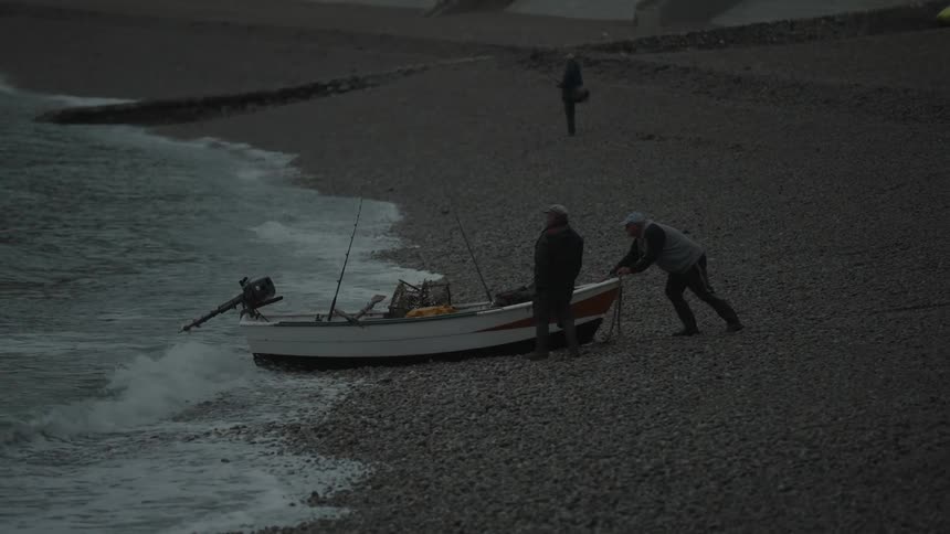 Fisherman launching his boat into the sea at a beach