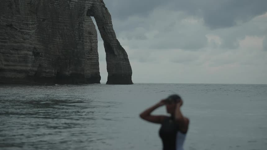 A female swimmer adjusts her swim cap while in the water