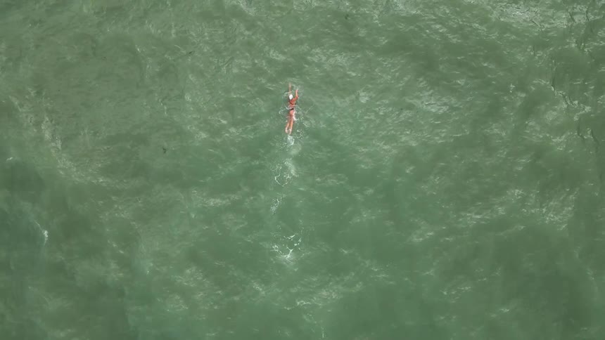 An aerial clip of a person swimming the ocean