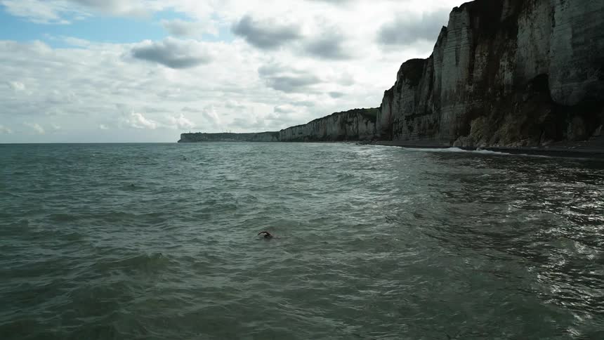 Woman swimming in the ocean next to the cliffs