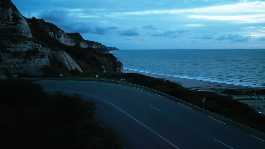 A deserted road on the coast of a beach with mountains